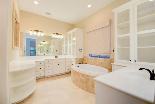 a spacious bathroom with double vanity a mirror a bathtub and a shower