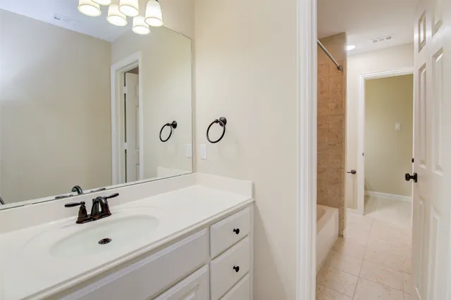 a bathroom with a sink vanity granite tub shower and a mirror