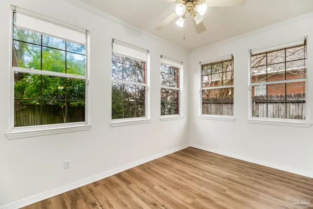 a view of empty room with wooden floor and fan
