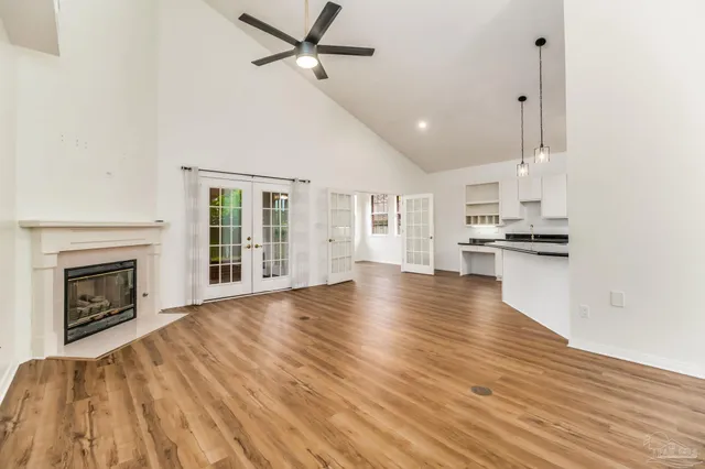 a view of an empty room with wooden floor fireplace and a window