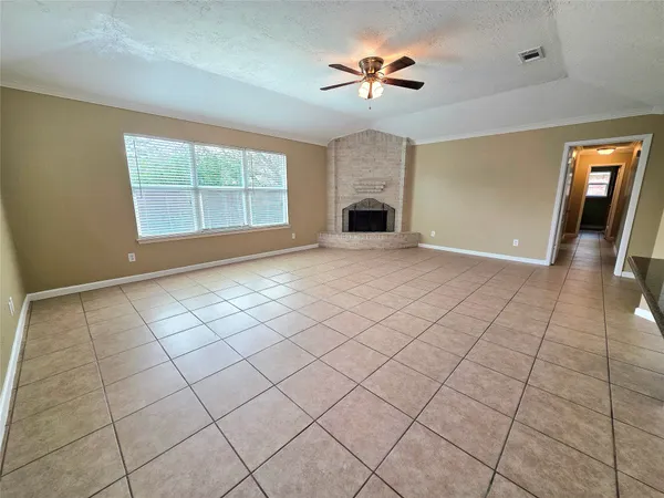 an empty room with chandelier fan and windows