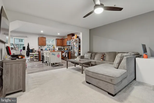 a living room with furniture and a dining table with kitchen appliances