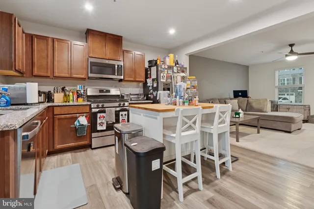 a kitchen with stainless steel appliances granite countertop a stove top oven a sink dishwasher and white cabinets with wooden floor