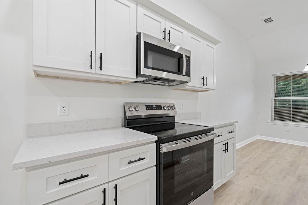 372 Edith Avenue Memphis, TN 38126 - Photo 22 of 23 Kitchen with stainless steel appliances, white cabinetry, light wood-style flooring, light stone countertops, and vaulted ceiling