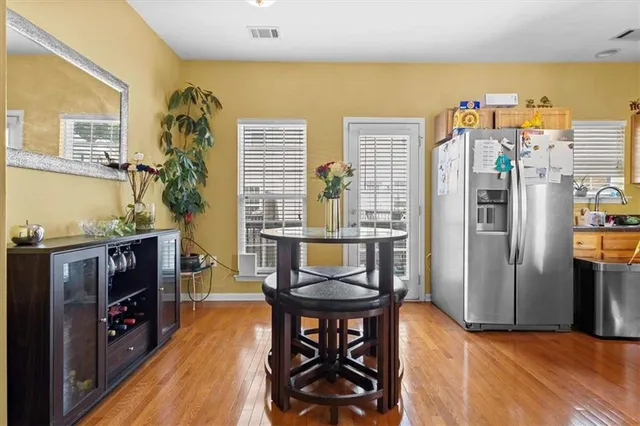 a kitchen with stainless steel appliances granite countertop a stove top oven a sink dishwasher a dining table and chairs with wooden floor