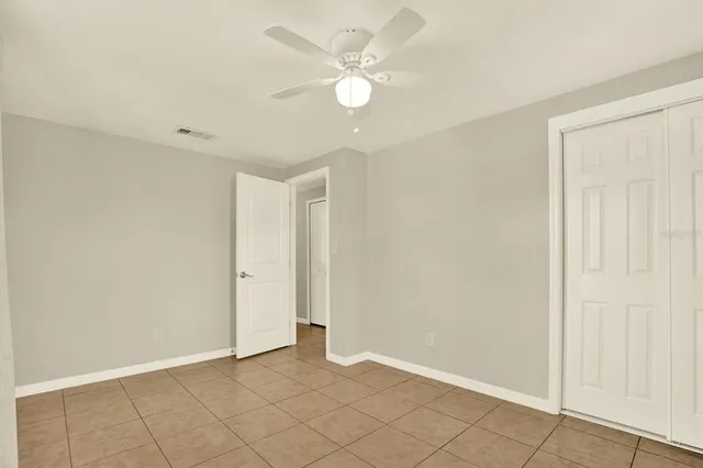 an empty room with closet and a ceiling fan