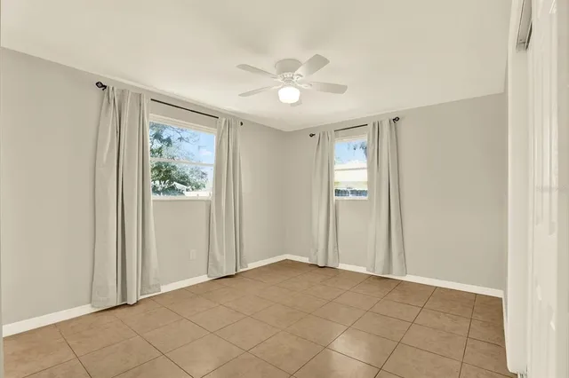 a view of an empty room with window and chandelier fan