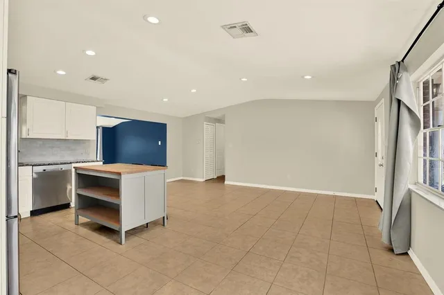 a living room with stainless steel appliances furniture and a kitchen view