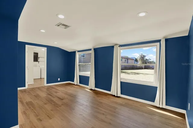 a view of an empty room with wooden floor and a window