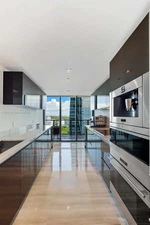 a large kitchen with a large counter top space a sink and stainless steel appliances