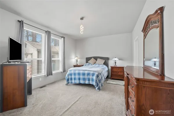 a bedroom with a bed and a flat tv screen on wall