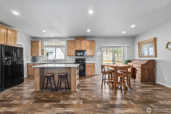 a dining area with stainless steel appliances granite countertop a dining table chairs refrigerator and sink