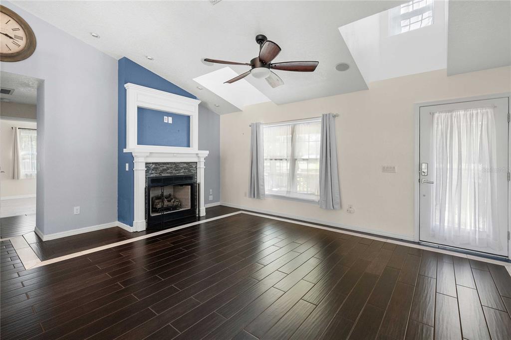 7037 County Road 625 Bushnell, FL 33513 - Photo 14 of 72 an empty room with wooden floor fireplace and windows