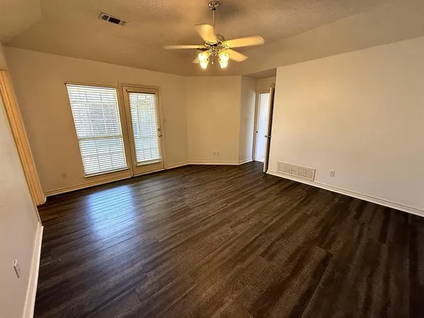 an empty room with wooden floor and windows