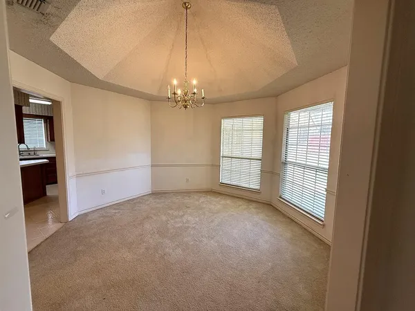an empty room with chandelier fan and windows
