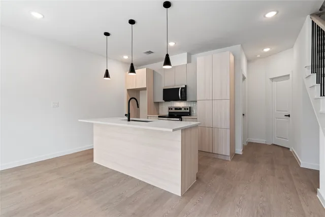 a view of kitchen with stainless steel appliances refrigerator stove and wooden floor