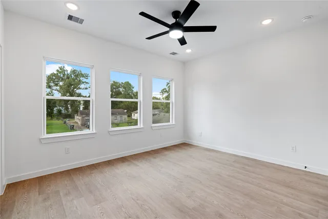 an empty room with wooden floor and windows