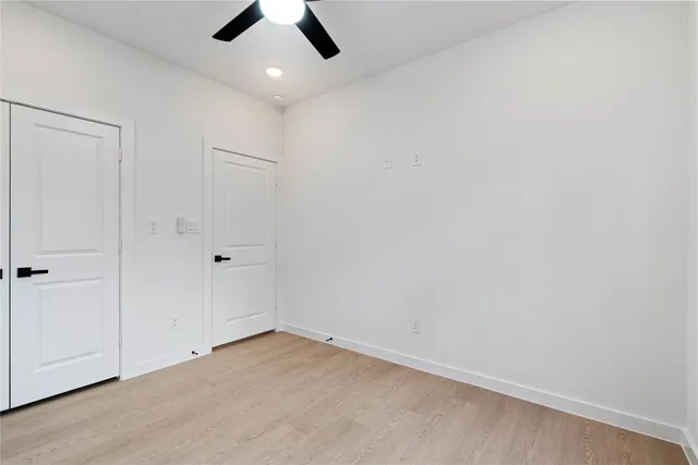 an empty room with ceiling fan and window