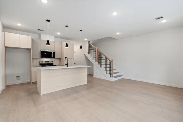 a view of kitchen with stainless steel appliances kitchen island refrigerator sink and cabinets
