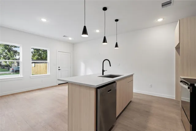 a kitchen with stainless steel appliances granite countertop a sink a window and a kitchen island