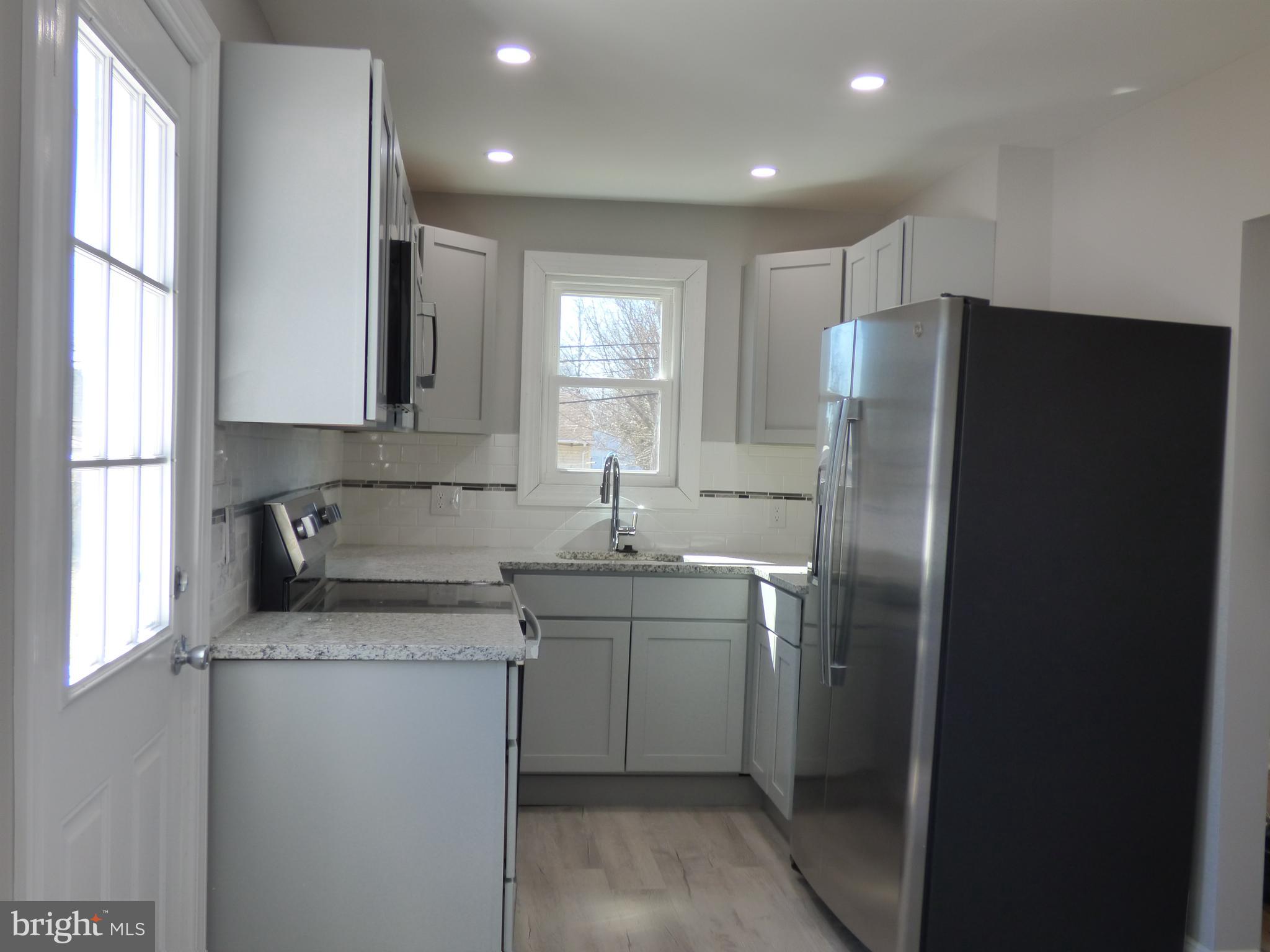 726 Newportville Road Croydon, PA 19021 - Photo 17 of 30 a kitchen with stainless steel appliances granite countertop a refrigerator a sink a stove a washer and dryer with wooden floor