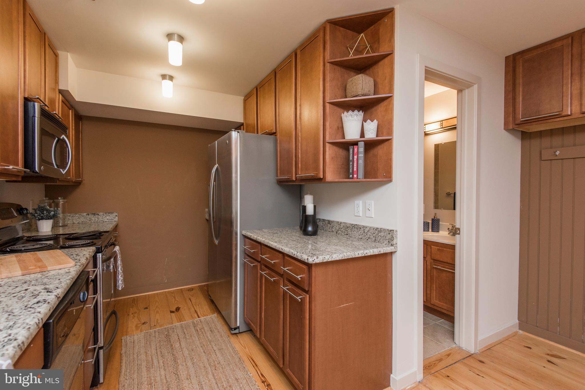 1200 Walnut Street, Unit 203 Philadelphia, PA 19107 - Photo 6 of 27 a kitchen with stainless steel appliances granite countertop a refrigerator a stove and a sink with wooden floor