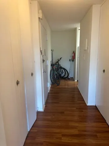 a view of a hallway with wooden floor and a bathroom