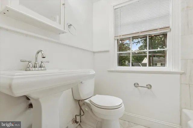 a bathroom with a sink mirror toilet and next to a window