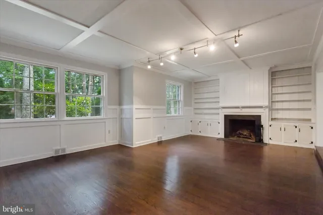 an empty room with windows fireplace and wooden floor