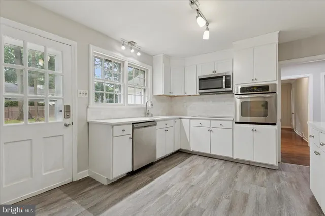 a kitchen with appliances cabinets and a wooden floor