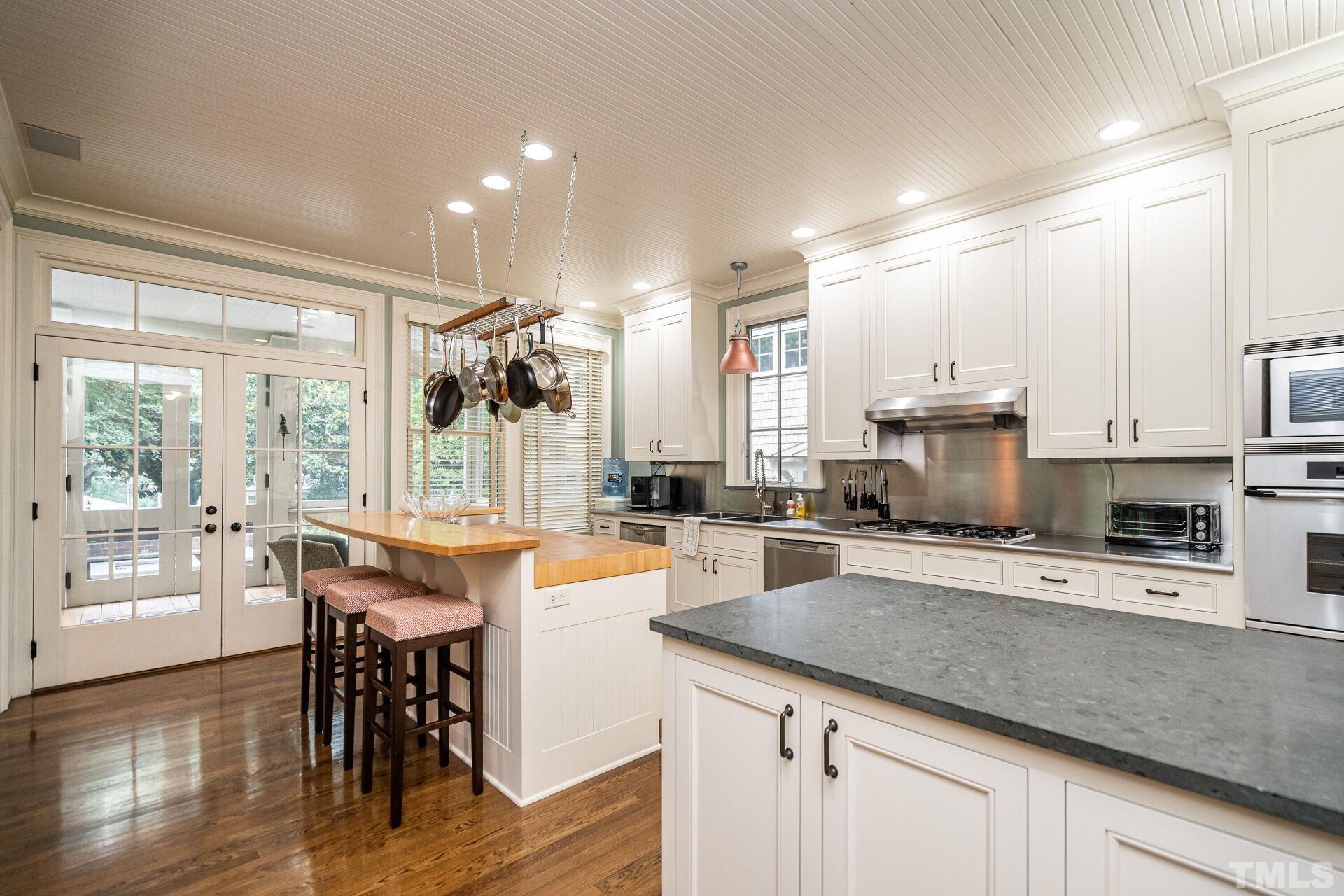 1027 Vance Street Raleigh, NC 27608 - Photo 15 of 42 a kitchen with stainless steel appliances granite countertop a stove top oven a sink dishwasher a dining table and chairs with wooden floor