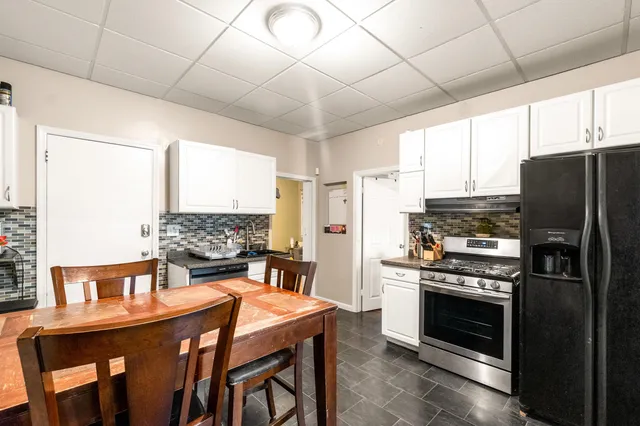 a kitchen with stainless steel appliances a stove a refrigerator and a dining table