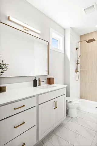 a bathroom with a double vanity sink a toilet and a shower