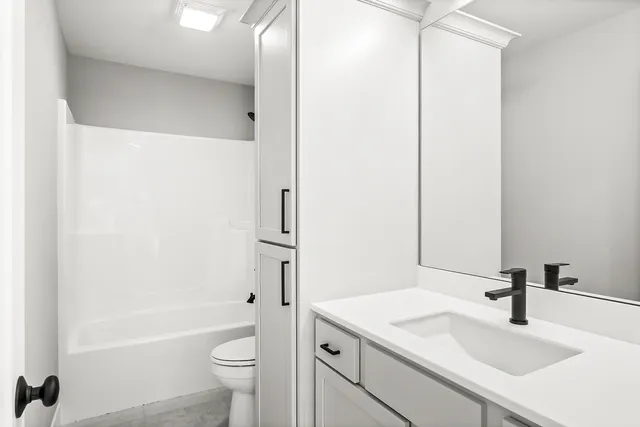 a bathroom with a granite countertop sink a toilet and a bathtub