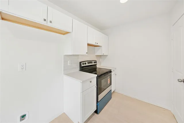 an empty room with wooden floor ceiling fan and windows