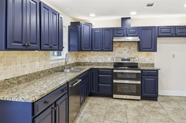 a kitchen with stainless steel appliances granite countertop wooden cabinets a stove and a sink