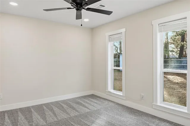 an empty room with windows and fan