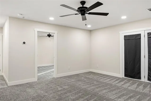 an empty room with a ceiling fan and carpet