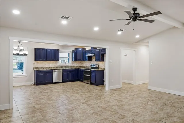 a large kitchen with a large counter top stainless steel appliances and cabinets