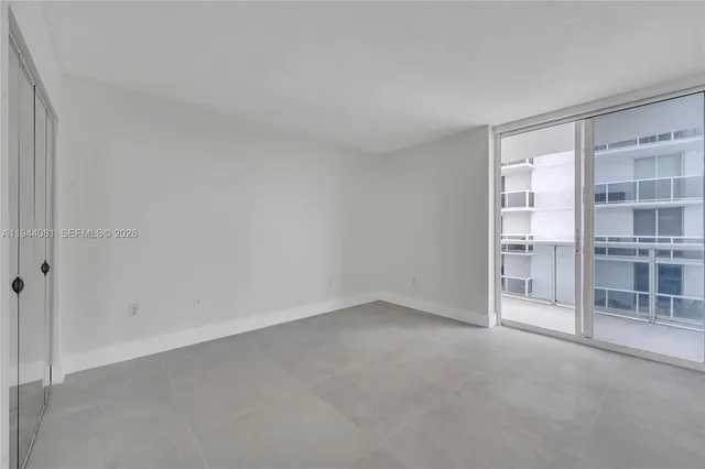 a view of an empty room with a window and cabinet