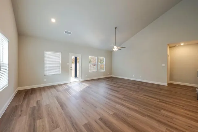 a view of empty room with wooden floor and fan