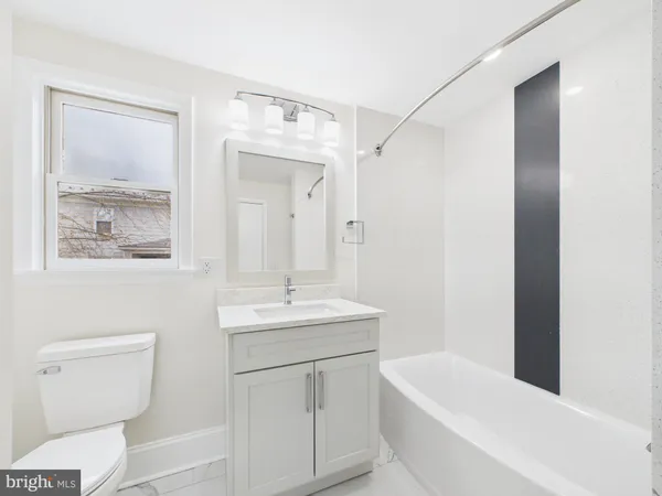 a bathroom with a toilet a sink a tub and mirror