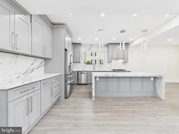a large white kitchen with kitchen island white cabinets and stainless steel appliances