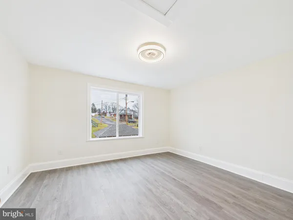 an empty room with wooden floor and window