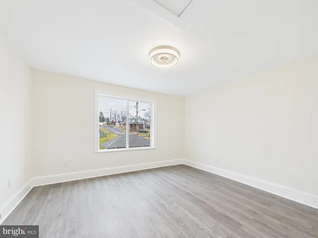 an empty room with wooden floor and window