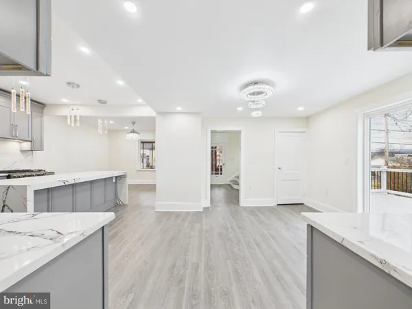 a large kitchen with stainless steel appliances a large counter top a sink dishwasher and a stove with wooden floor