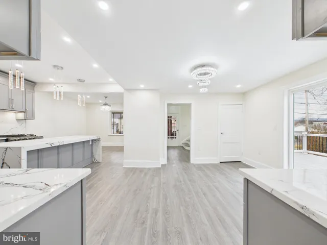 a large kitchen with stainless steel appliances a large counter top a sink dishwasher and a stove with wooden floor