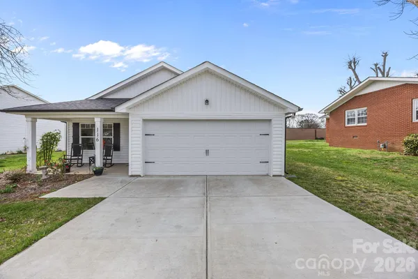 a view of a house with a yard plants and large tree