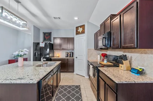 a kitchen with granite countertop kitchen island stainless steel appliances a sink stove and refrigerator