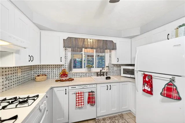 a kitchen with kitchen island granite countertop a sink appliances cabinets and a large window